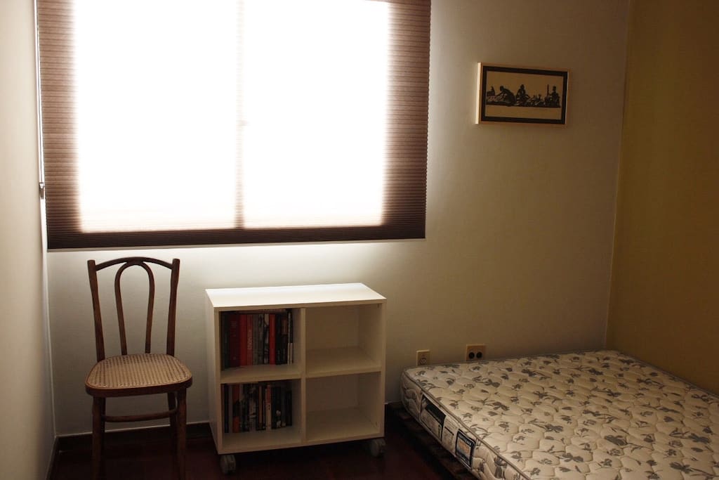 quarto com colchão de casal em cama de pallet, ventilador, blackout e cortina plissada. neste quarto, é possível acomodar uma 3a pessoa em colchão de solteiro no chão