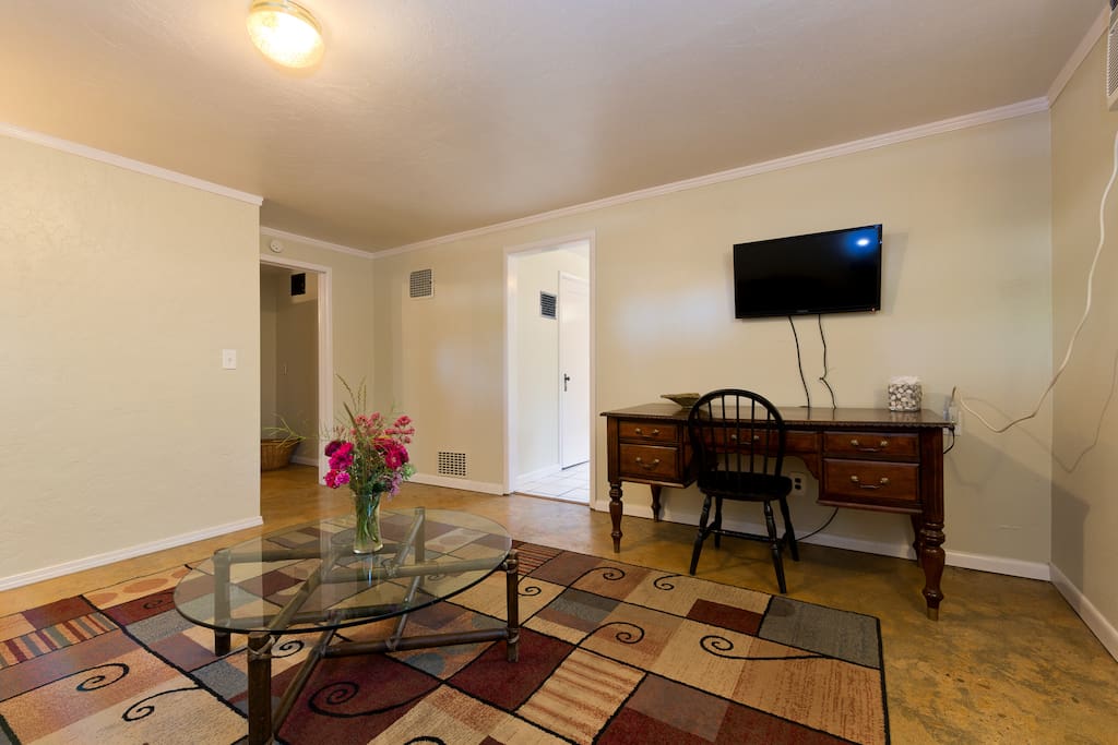 Living room with large desk and TV w/ HDMI/DVD and wall heater and A/C