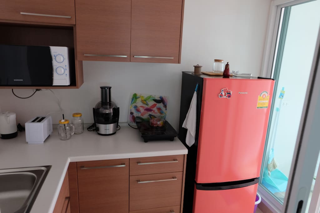 Kitchen equipped with refrigerator, fresh fruit juicer, toaster, microwave, kettle and induction table