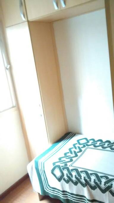 Quarto de solteiro, com armário embutido e cama.