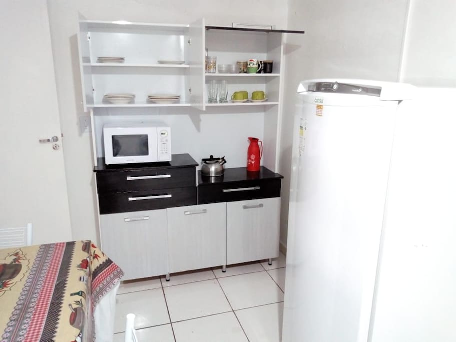 Geladeira, micro ondas e utensílios de cozinha.