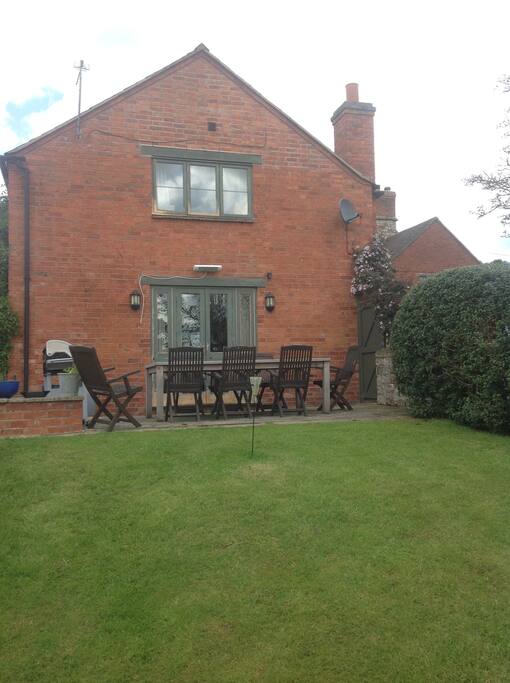 Front view of the house. French Windows leading to sitting room. Outside seating and BBQ
