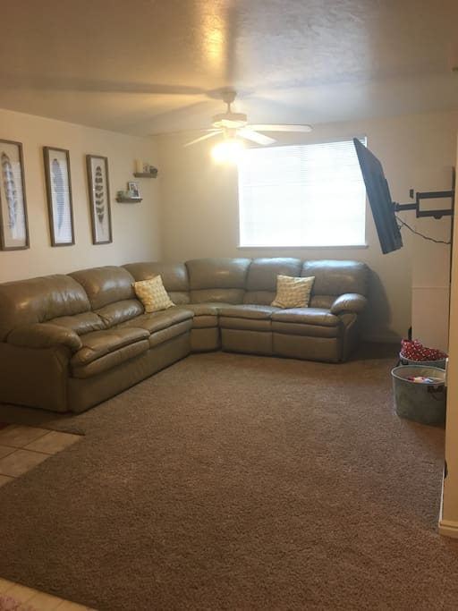 living room with large sectional including hide-a-bed and two recliners, 55 inch TV with access to Xbox One (with netflix and hulu), directTV, and a DVD player