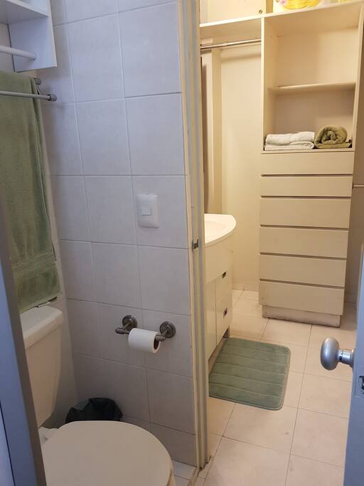 Regadera y baño dentro de la habitación con cajoneras y percheros.