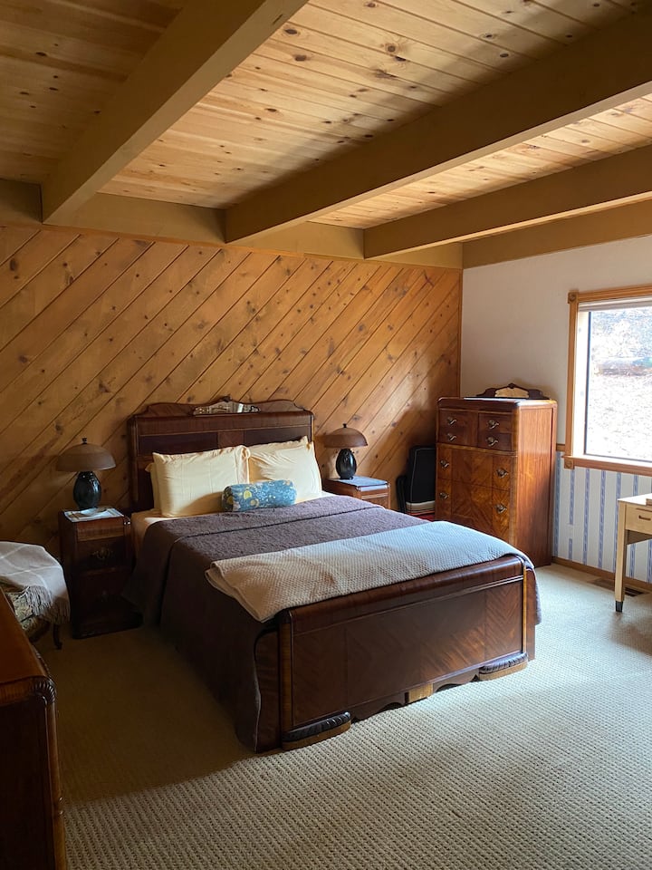 Cómoda cama tamaño queen en el dormitorio principal, con una hermosa vista del bosque circundante 