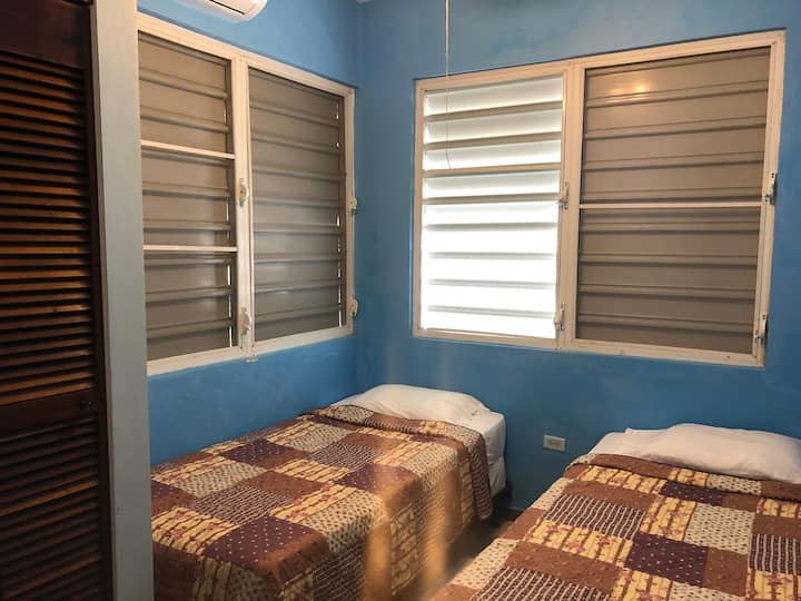 Segundo dormitorio sencillo con dos camas individuales y aire acondicionado.