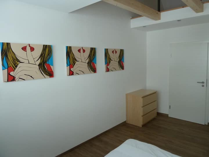 Das zweite Schlafzimmer mit grosser Fensterfront Doppelbett, Kommode und Kleiderschrank.