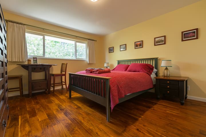 Spacious bedroom with beautiful wood floors and a window full of flowers!
