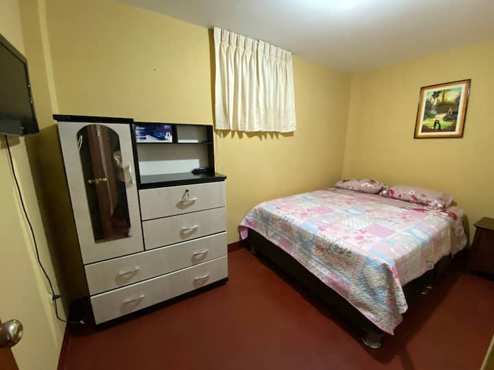 Silid - tulugan na may king - size na higaan, muwebles, at TV