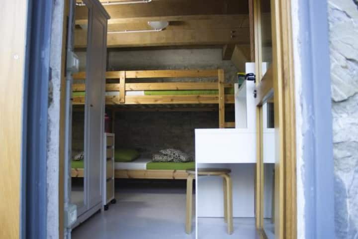 Chambre avec lit superposé, bureau, armoire et accès direct à l'espace extérieur