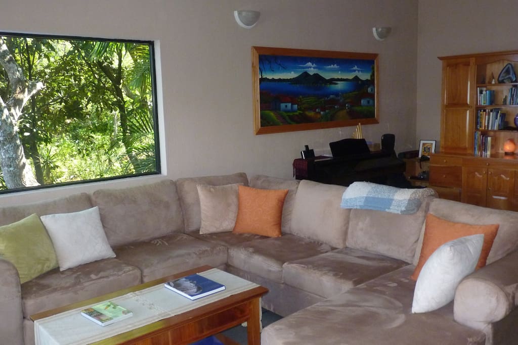 Living room, with fireplace, piano, with lake and garden views. The house is decorated with paintings and textiles by local artists and weavers