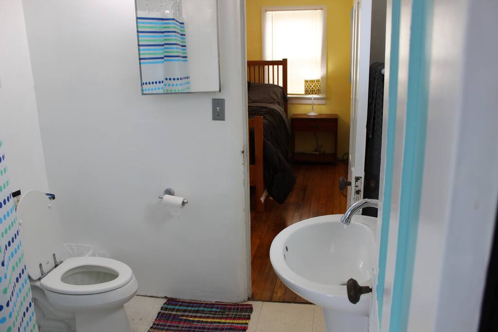 Fully functional bathroom with pedestal sink, rounded shower, and toilet.