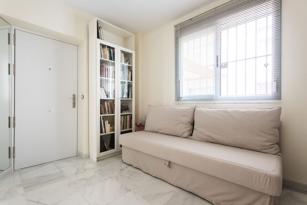 Ángulo de salita-dormitorio desde el que se ve la puerta de entrada al apartamento.