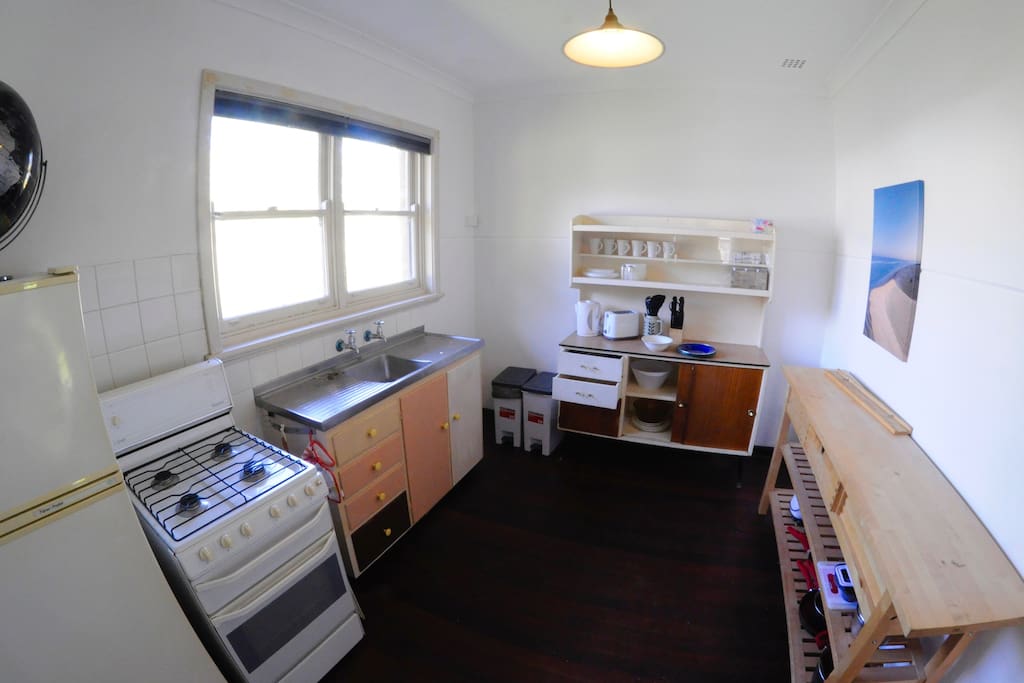 the kitchen with a view of the tree-lined street. Gas stove, refrigerator, microwave, kettle and toaster.