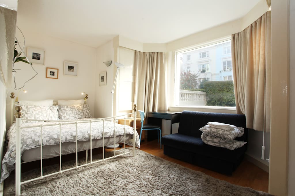 Spacious and luxurious bedroom with comfortable sofa that opens up into a small double sofa bed.