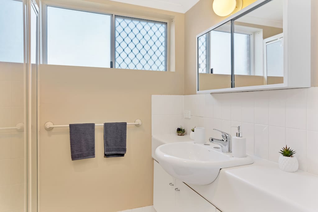 Clean, modern bathroom with large shower + laundry