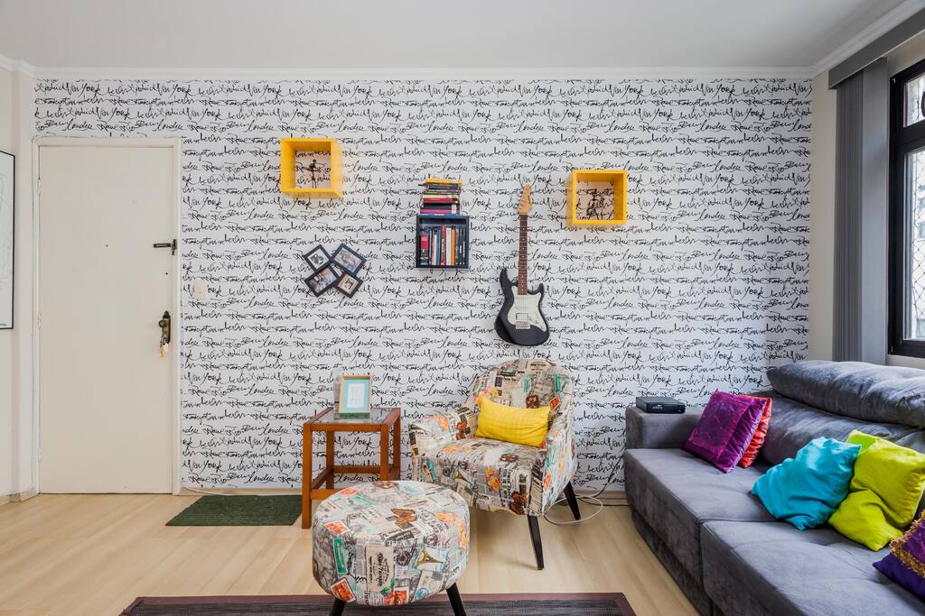 Sala de estar/TV. Parede Cidades do Mundo (se você ficar aqui em casa, vou conseguir conhecer algumas delas). Sofá cama (maravilha pra se jogar depois de um dia cansativo). Poltrona com Puff logo abaixo dos livros pras vibes cultura.