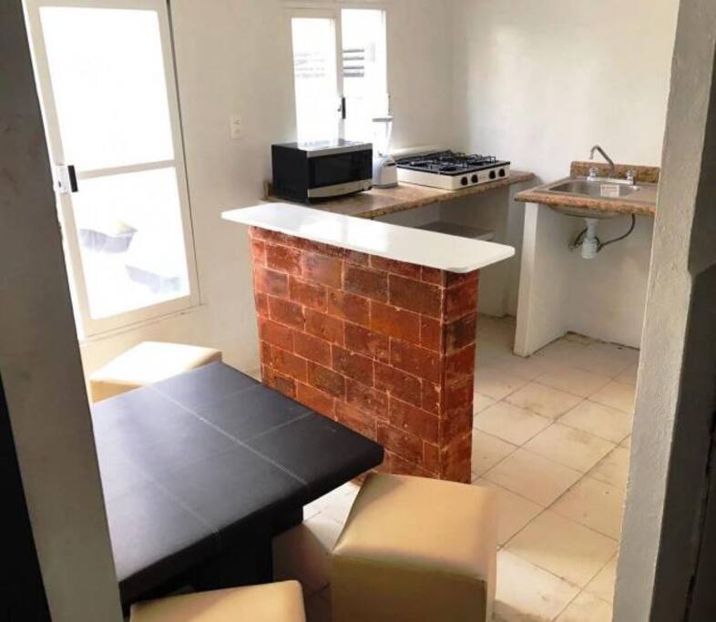 Cocina con refrigerador, licuadora, microondas, parrilla y lavabo, con desayunador