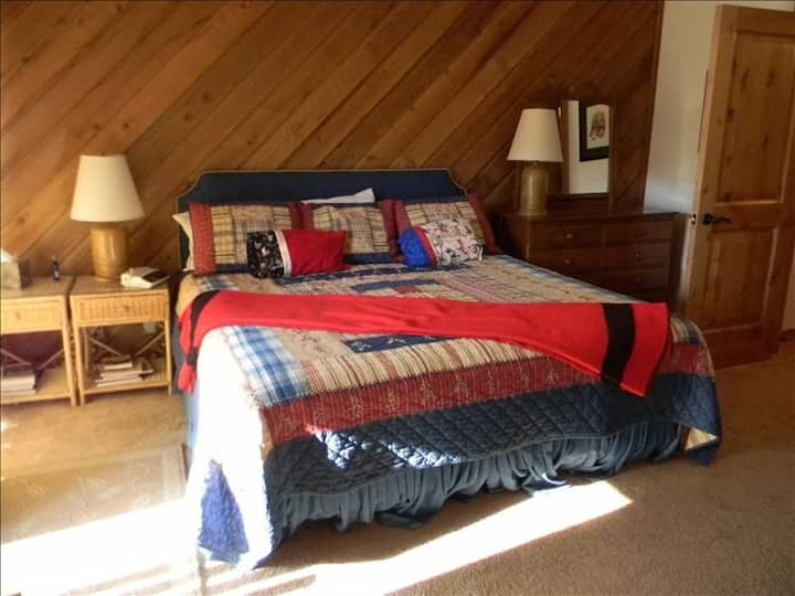 Chumba cha kulala cha bwana mfalme kilicho na bafu la ndani, beseni la kuogea  na vyumba vyenye nafasi kubwa.  Deki iko nje ya mlango wa kuteleza.
