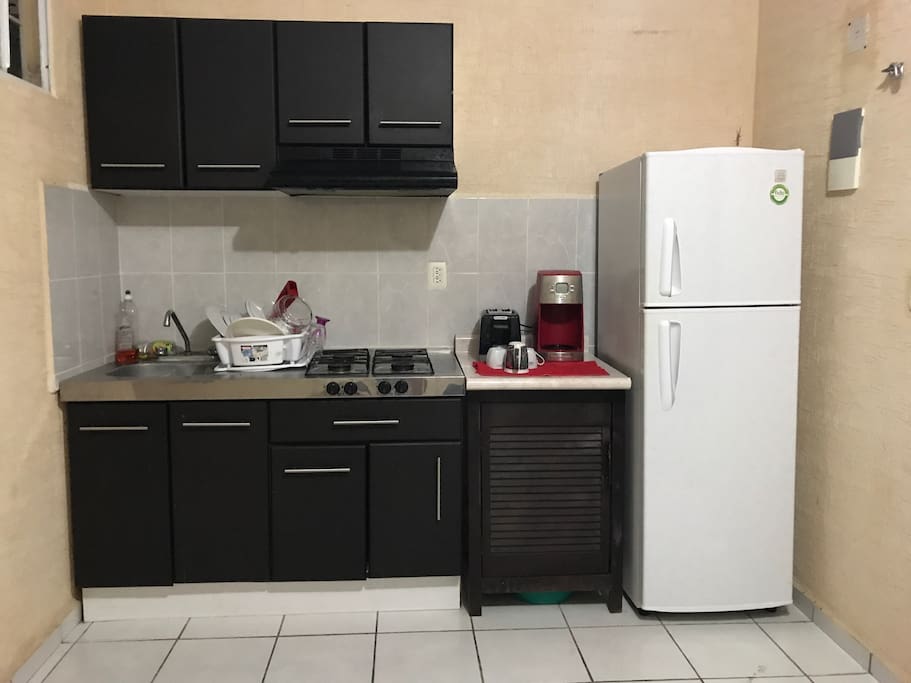 Cocina con cafetera, tostadora, refrigerador y todos los utensilios de cocina.