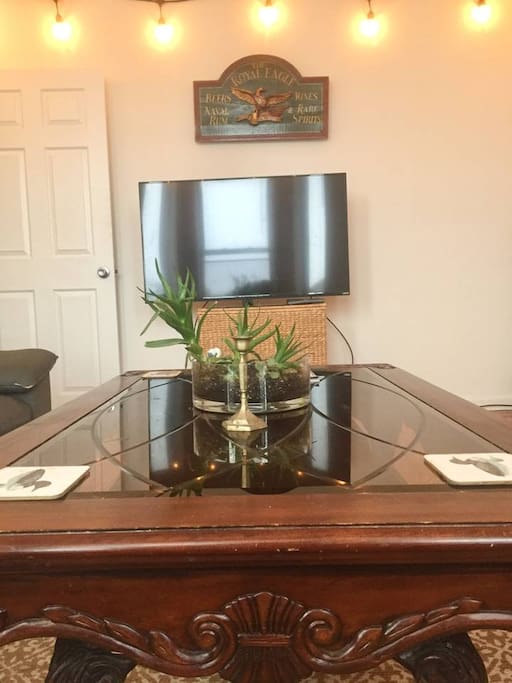 Mahogany and glass living room table with succulent bowl. My antique tavern sign is above the tv -- you're welcome to watch.