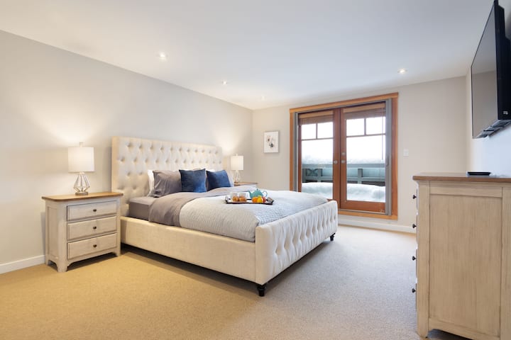 Dormitorio principal con cama king, patio privado con vistas al campo dorado y Green Lake, con TV y cable montados.