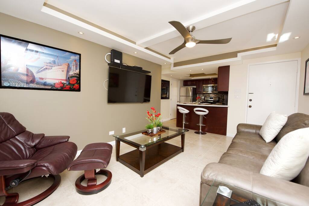 The living room has a 60" 4K smart TV. It is also equipped with a window AC.