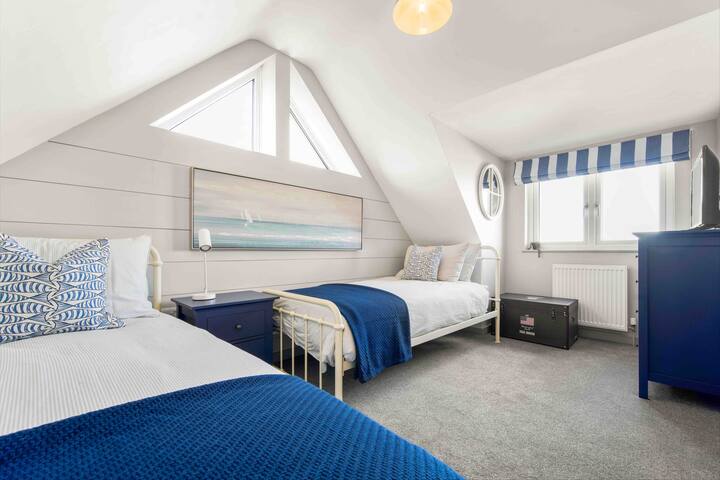 Chambre à deux lits au rez-de-chaussée avec Sky TV et un coffre de jouets, de livres et de jeux pour enfants.