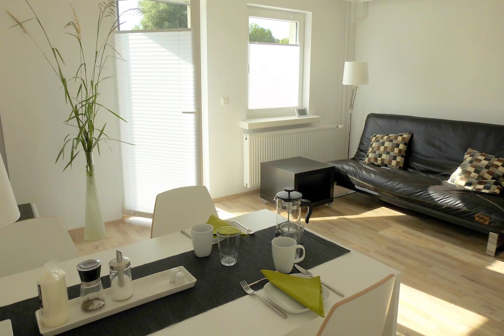 großes Wohnzimmer mit gemütlicher Couch und Esstisch für 4 Personen