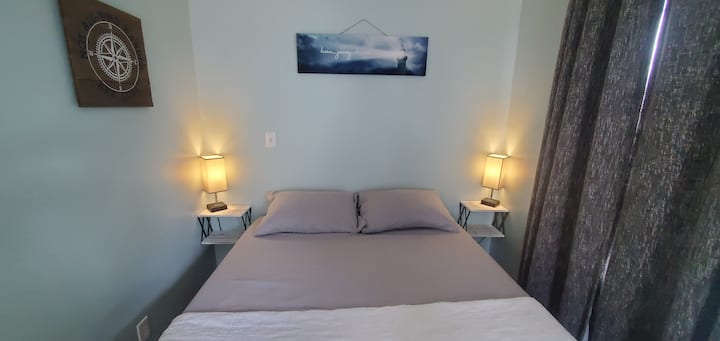 El dormitorio principal tiene una cama tamaño queen y cortinas que oscurecen la habitación. 