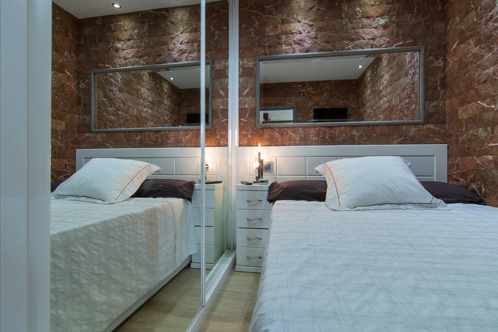 Dormitorio con cama de matrimonio con armario empotrado con enormes espejos que permiten ver el mar desde la cama.