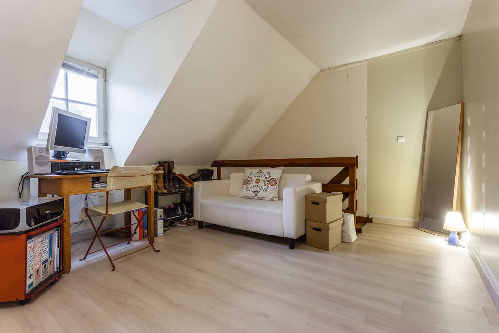 The other side of the upstairs bedroom. Couch, computer, full length mirror and stairs going down.