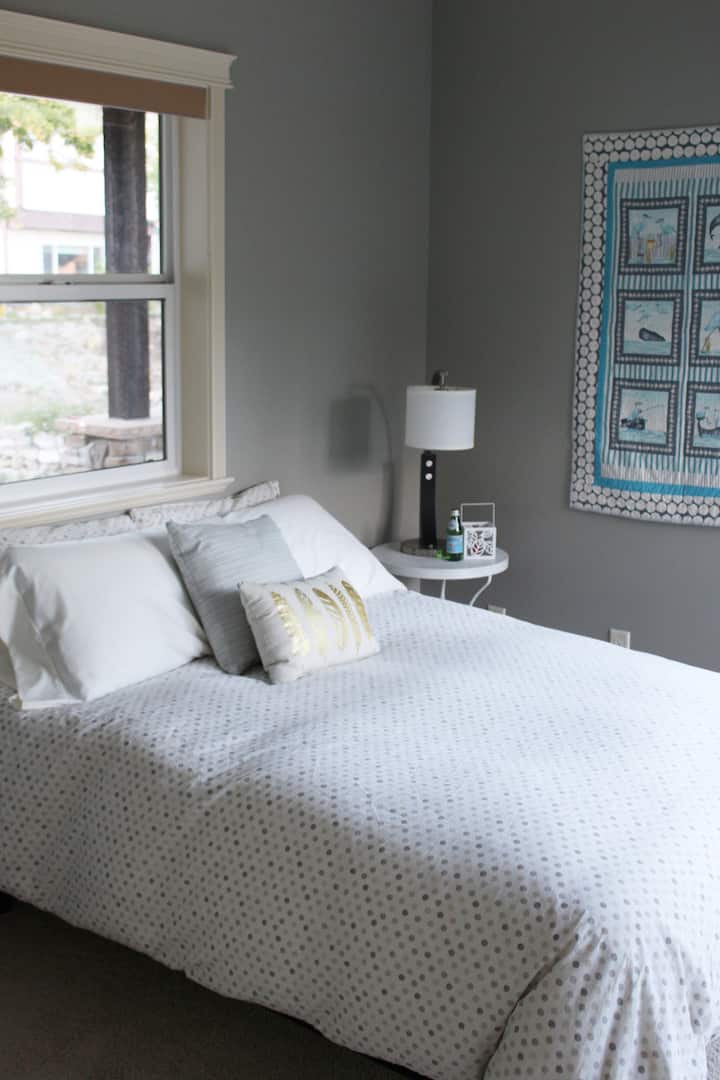 חדר שינה בקומה הראשית ליד הסלון. מיטה זוגית חדשה עם כרית עליונה