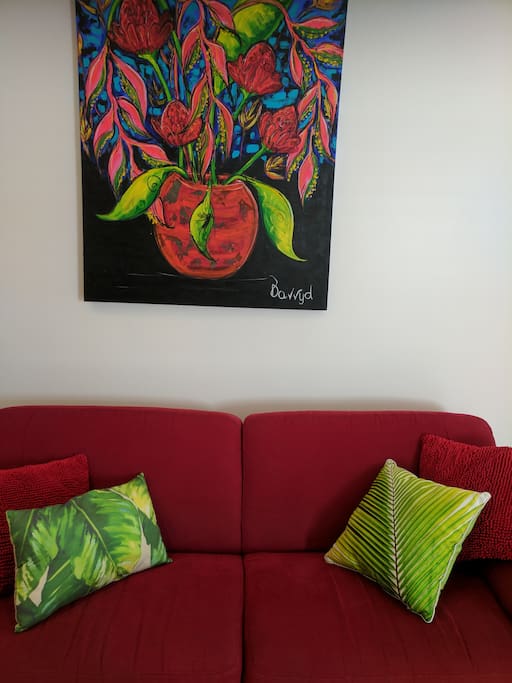 Red couch with tropical art work by local artists.