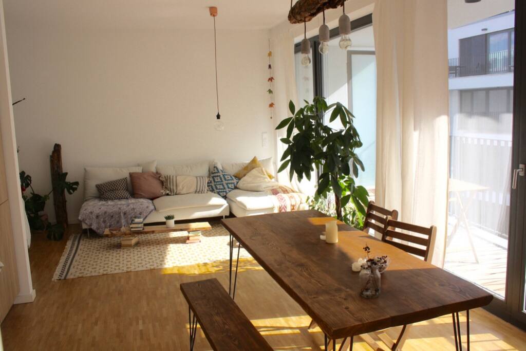 This is the big living room with a sofa, a dining table, an entrance area and an open kitchen.