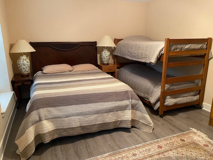 Segundo dormitorio con una cama tamaño queen y literas.