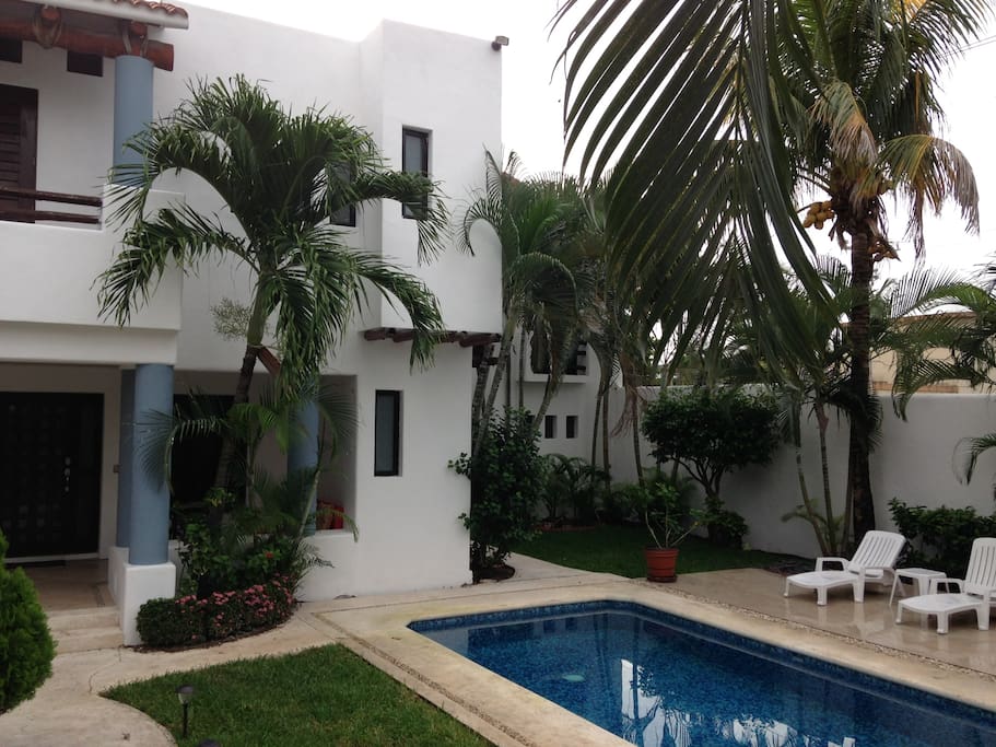 Spacious pool with lounging patio and palapa with hammocks.
