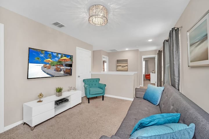 El loft se encuentra justo en la parte superior de la escalera. Tiene un sofá cama doble, una silla de esquina verde azulado y un televisor inteligente. La habitación tiene amplia luz natural con tres grandes ventanas detrás del sofá cama. 