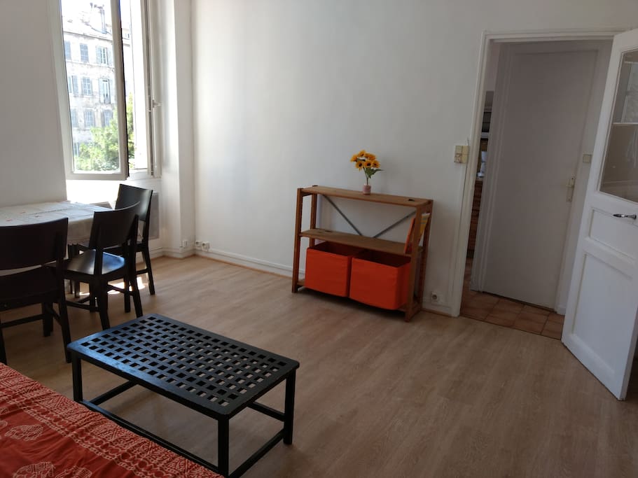 Salon vu du canapé avec accès cuisine et salle d'eau