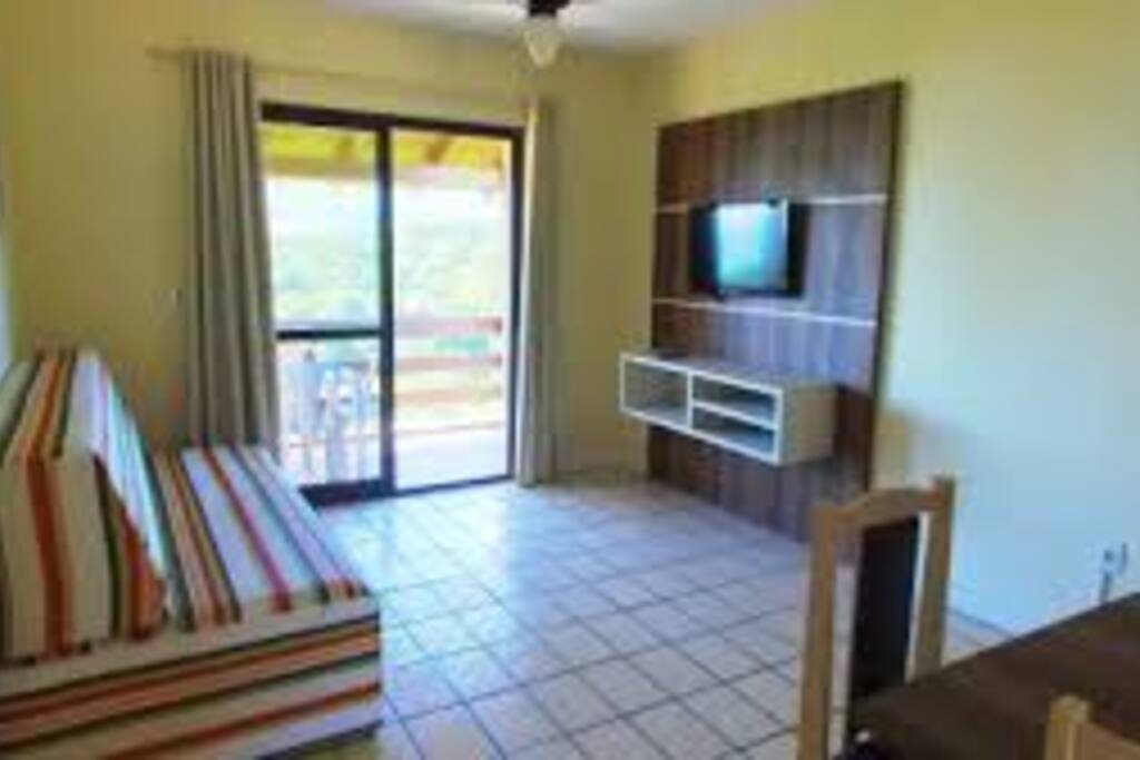 Sala com sofá cama, TV e mesa de jantar