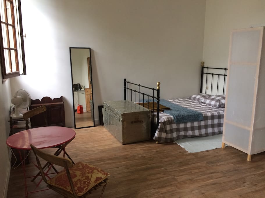 Queen size bed and small hanging closet that creates a private space for sleeping - photos do not illustrate bedding as the bedding is changed after each set of guests! Eating and sitting area furnished with vintage chairs and a beautiful painting signed by the artist