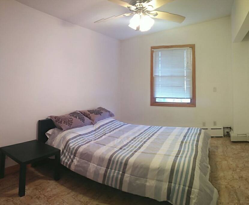 Cozy bedroom with angled ceiling, a queen sized bed, and a view out the window.