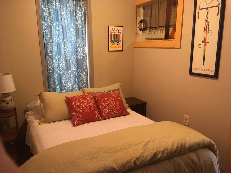 Small bedroom with double bed attached to kitchen. Small closet with hangers. Iron and ironing board.