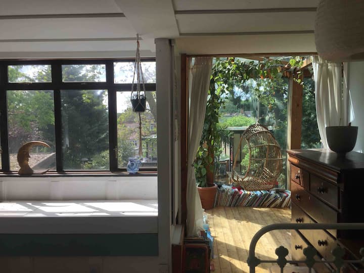 Amplio dormitorio principal hasta el primer piso.
Vista entre las copas de los árboles con acceso a un entrepiso en el atrio de vidrio que sobresale de la sala de estar y la escalera de caracol.
Ten en cuenta las ventanas brillantes y la falta de cortinas (su altura da privacidad).
