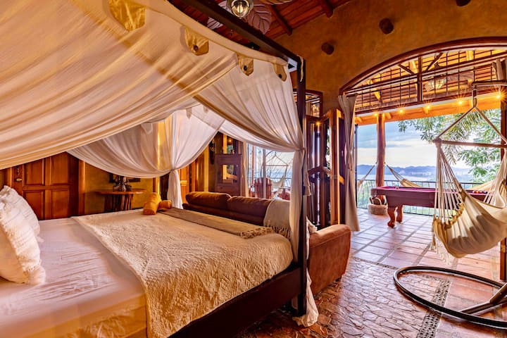 Hoofdslaapkamer op de tweede verdieping met directe toegang tot het terras van de tweede verdieping. Uitzicht op de oceaan-, jungle- en stadshemellijn. Kingsize bed en eigen badkamer