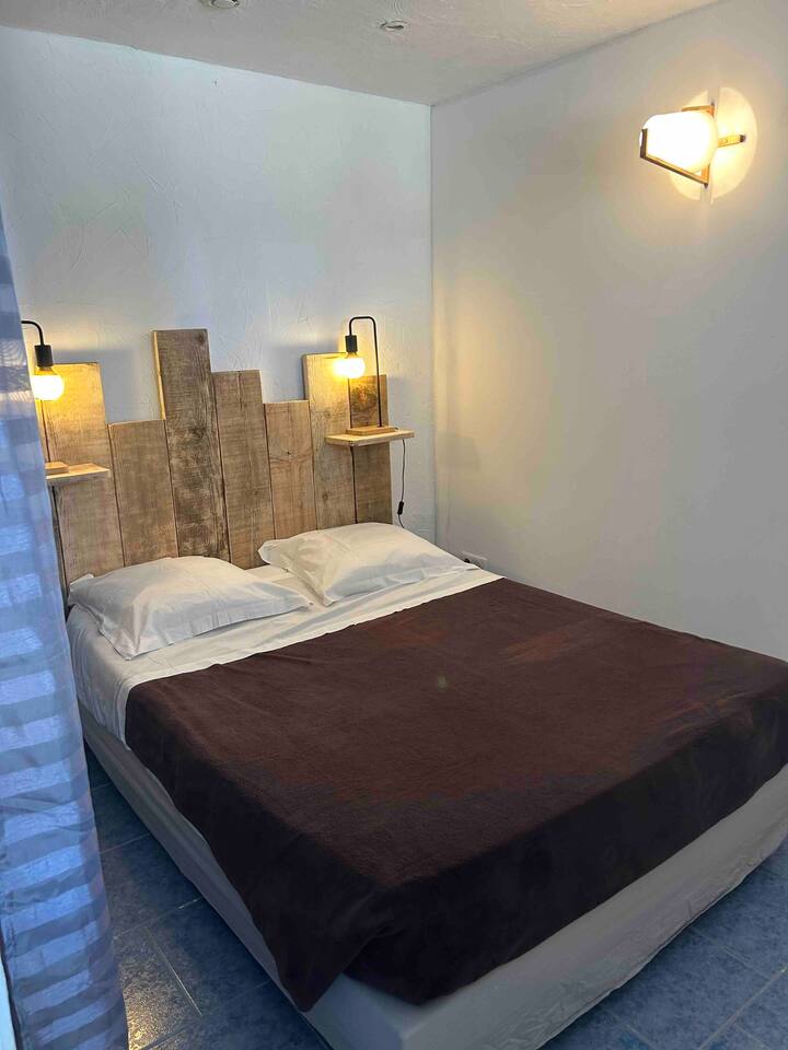 חדר שינה עם מיטה בגודל 140x190. ארון עם מדף. חצי מחיצה משותפת עם סלון 