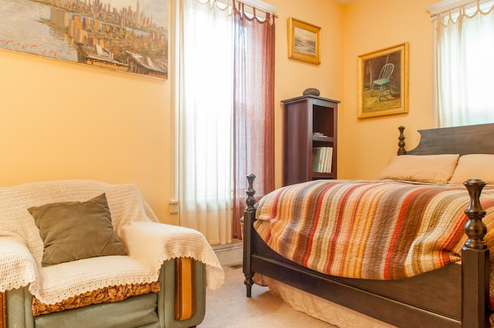 Првата спална соба има целосна големина, кадифен кревет и удобен стол за читање.