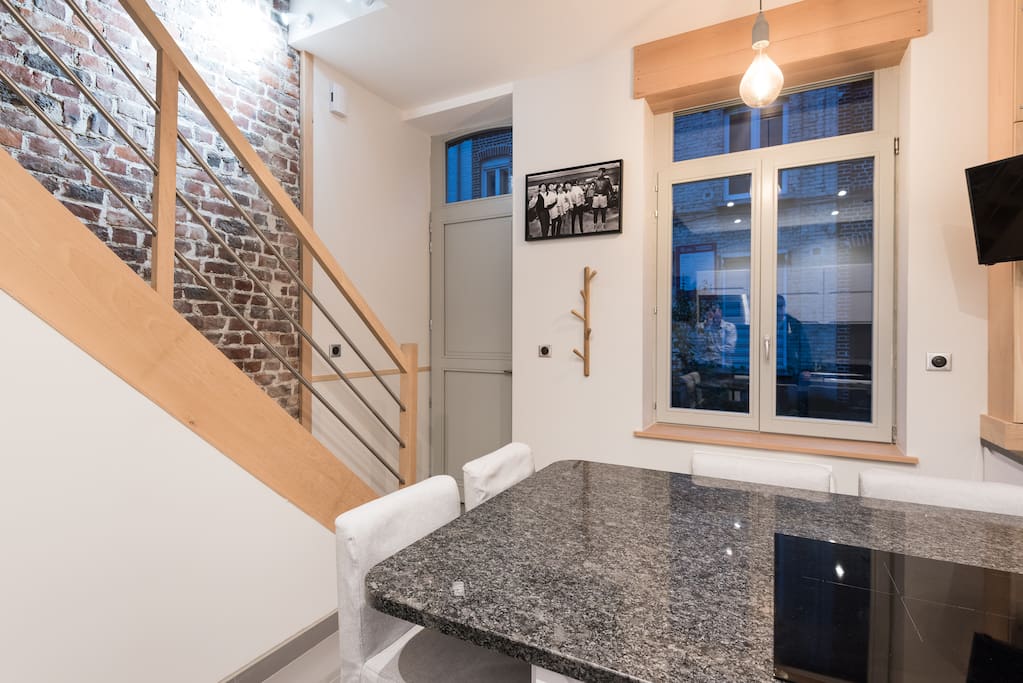 Cuisine - îlot moderne en granit noir, équipé d'une plaque à induction, il y a une grande surface pour manger. Située au RDC, c'est aussi l'entrée. La fenêtre est bien sécurisée, avec volet roulant électrique extérieur.