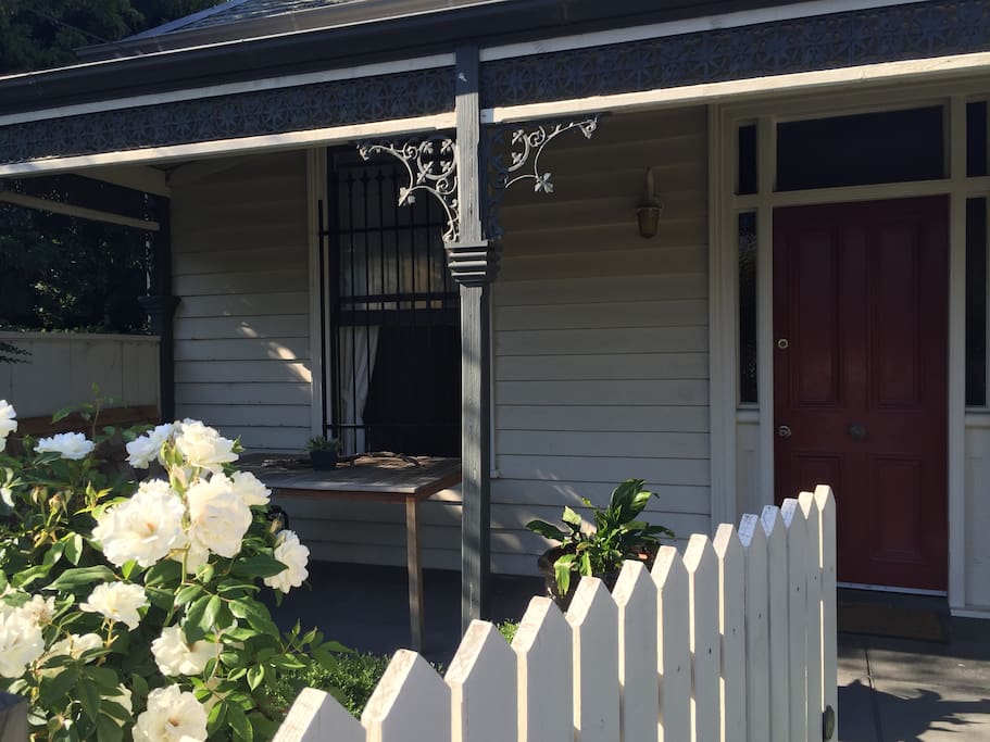 White picket fence, roses in bloom, front gate looking at the front door.