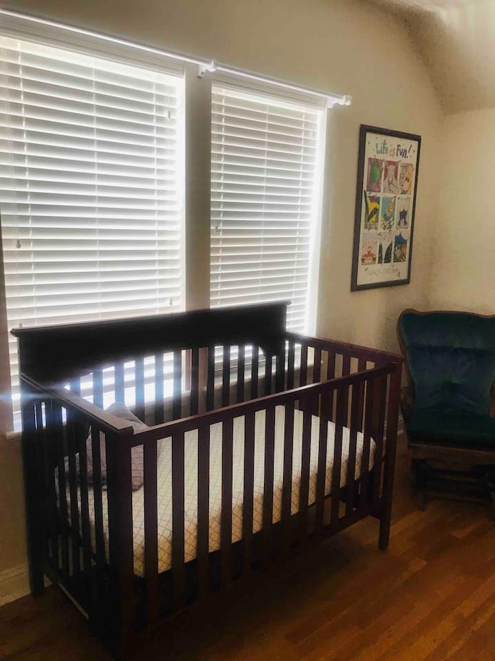 Baby crib located in children’s bedroom next to bunk beds